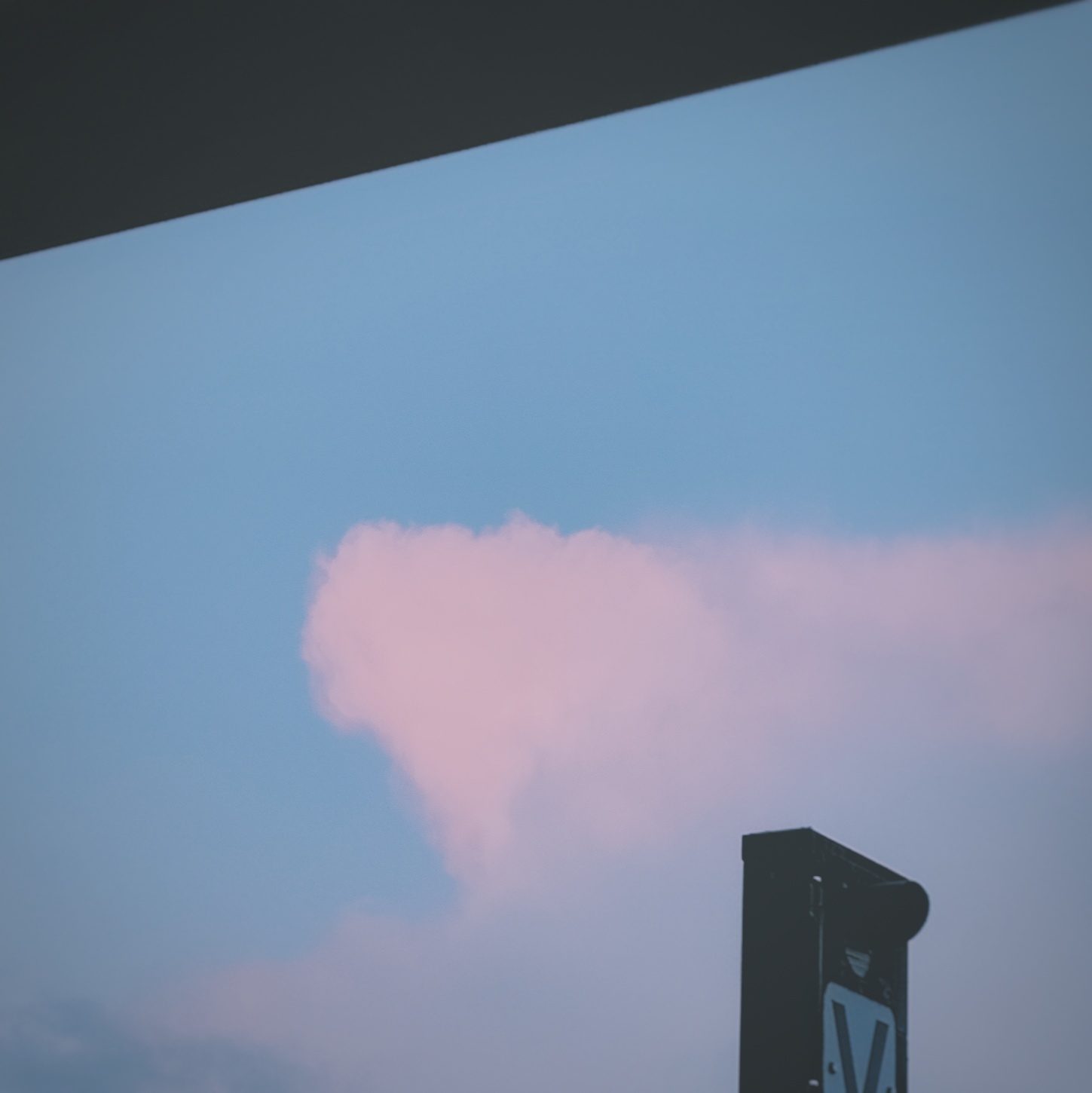 Pink cloud against dusk sky over rooftop