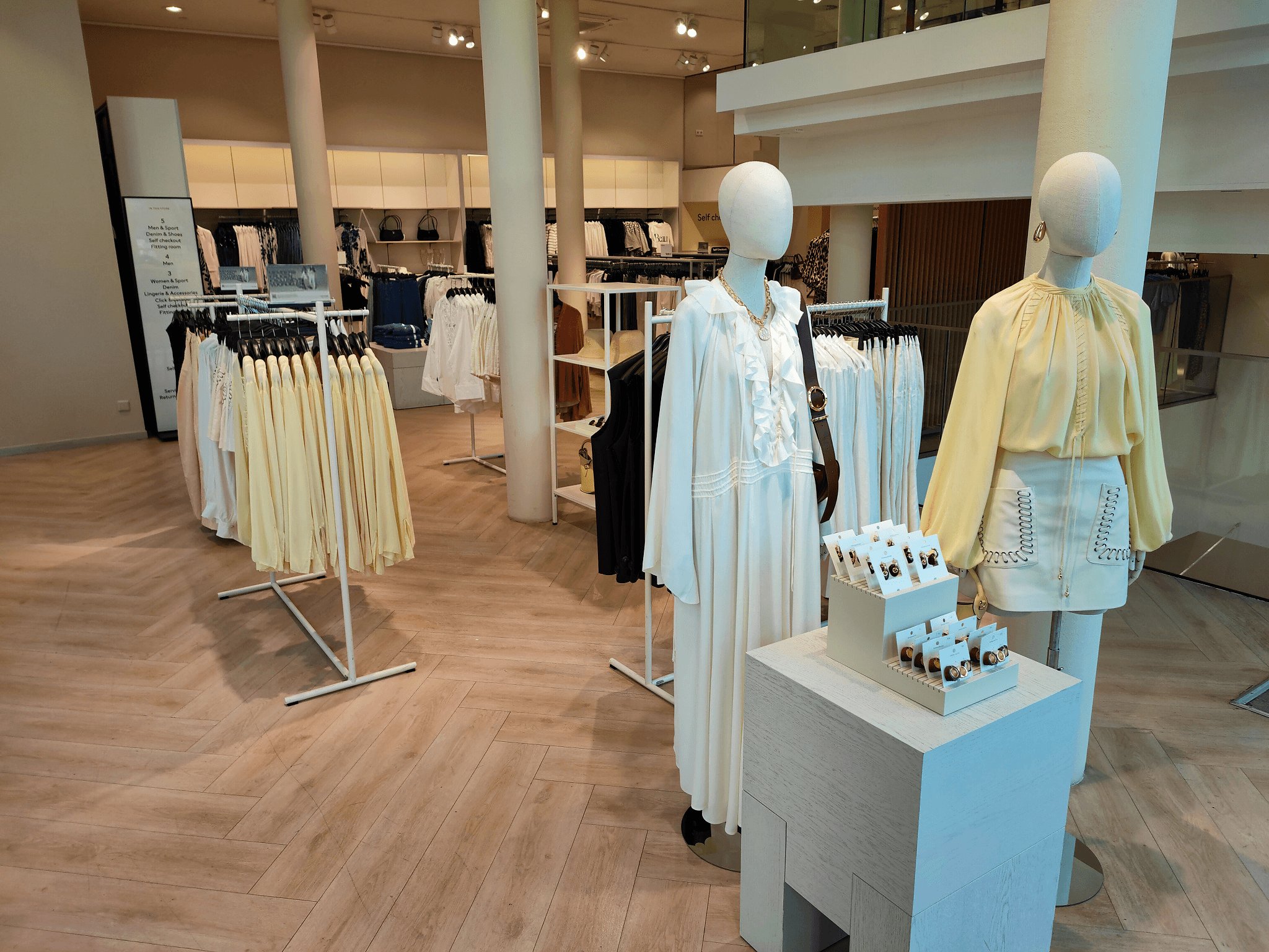 H&M Dam floor wide — plinth, racks, escalator sightline
