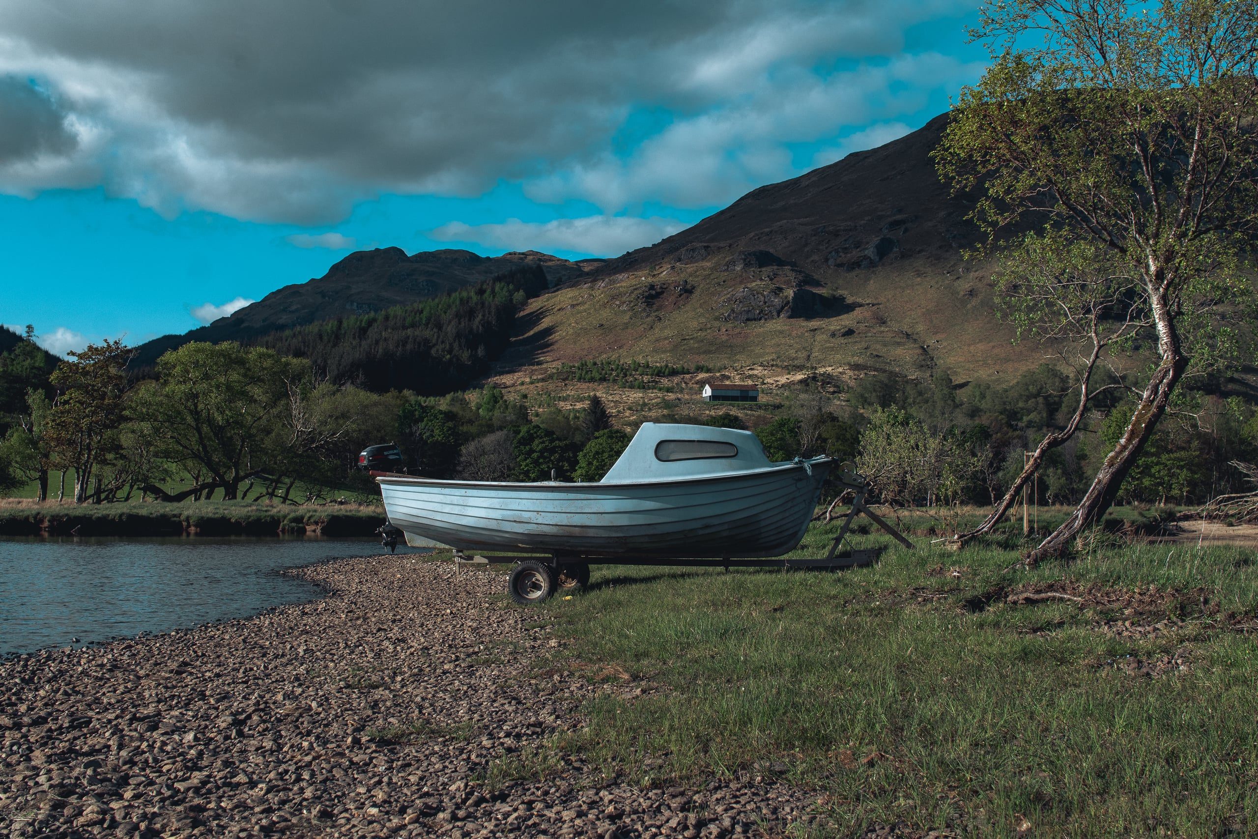 Wooden boat beached by Highland loch with clouded sky