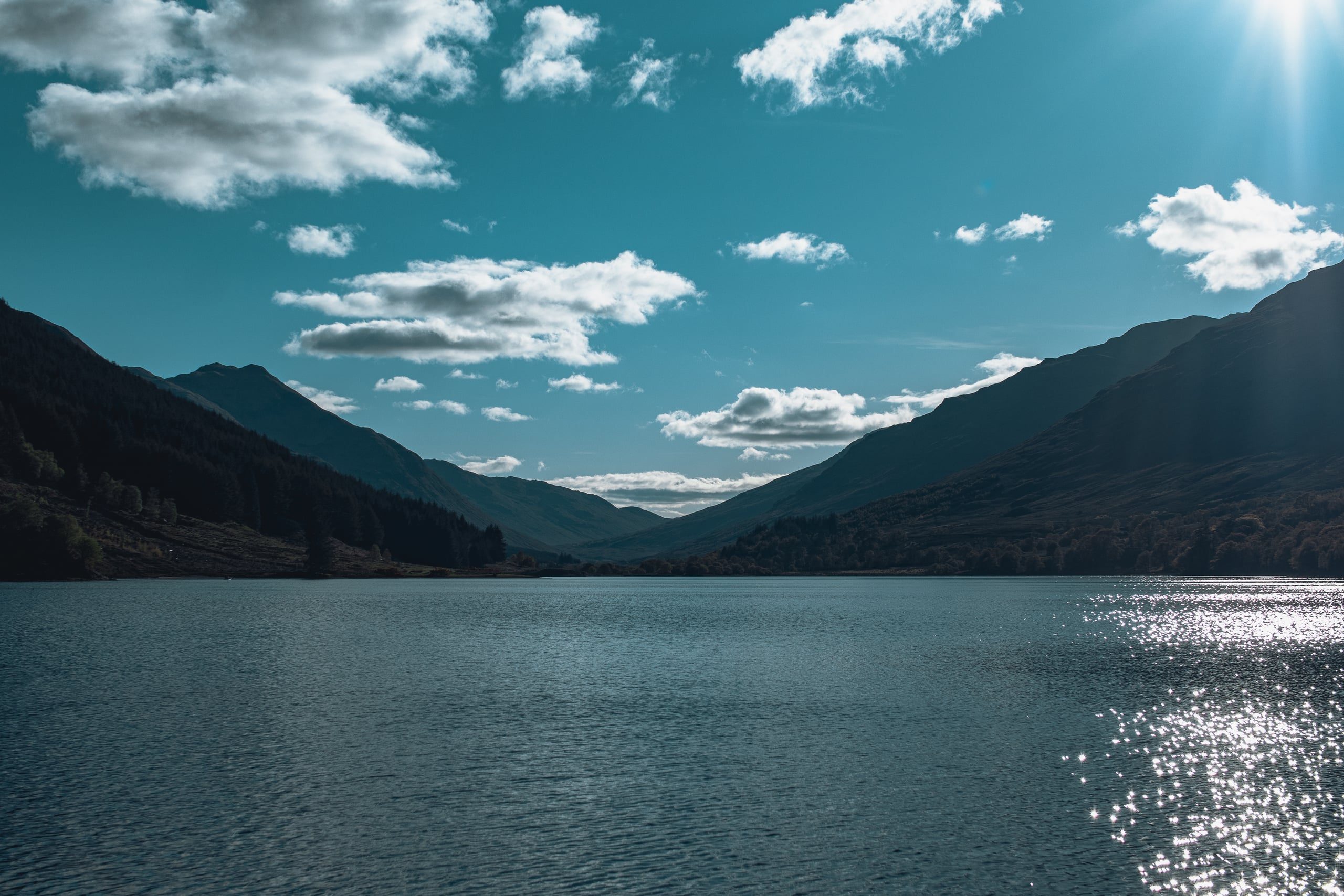 Highland loch in afternoon sun, mountains silhouetted